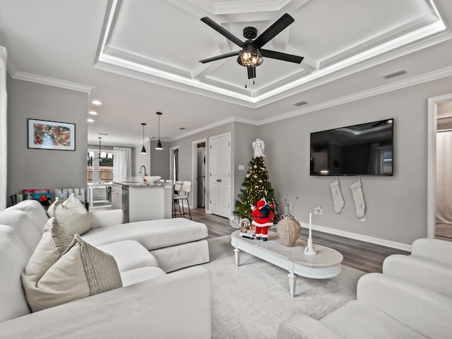 living room featuring ceiling fan with notable chandelier, sink, ornamental molding, and dark wood-type flooring