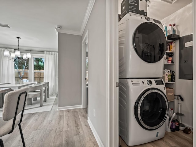 laundry area with crown molding, light hardwood / wood-style flooring, stacked washer and clothes dryer, and an inviting chandelier