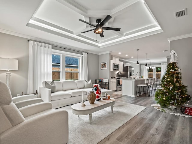 living room featuring ceiling fan, wood-type flooring, crown molding, and a wealth of natural light