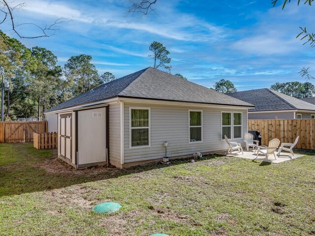 rear view of house with a lawn, a storage unit, a fire pit, and a patio area