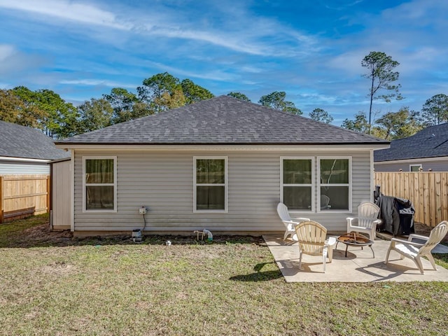 back of house featuring a lawn, a patio, and an outdoor fire pit