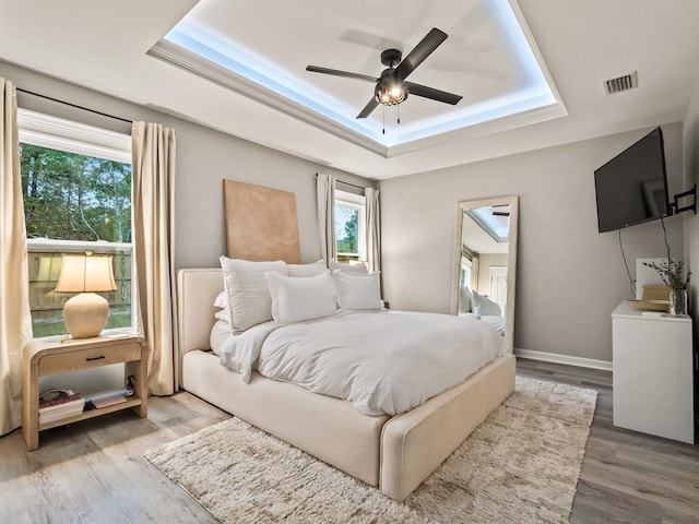 bedroom featuring a raised ceiling, ceiling fan, and hardwood / wood-style floors