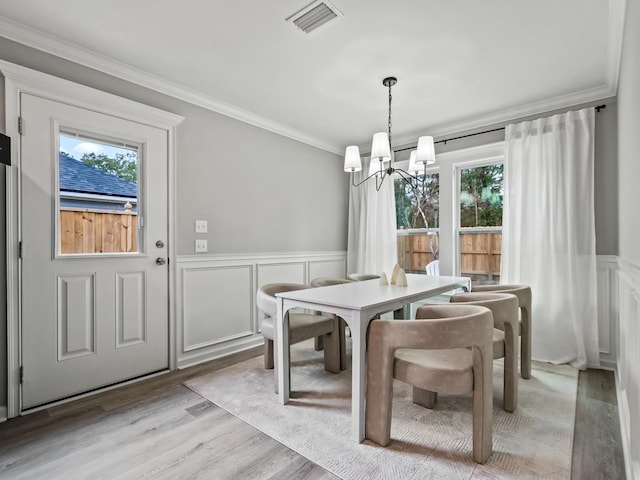 dining room featuring crown molding, plenty of natural light, a notable chandelier, and light wood-type flooring