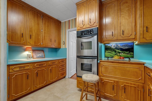 1540 Isabel Ct, Tallahassee, FL 32303 - kitchen featuring stainless steel double oven, brown cabinets, light countertops, and crown molding