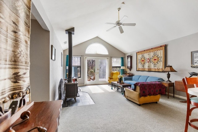 carpeted living room featuring high vaulted ceiling, french doors, ceiling fan, and a wood stove