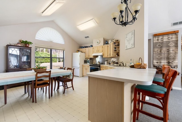 kitchen with appliances with stainless steel finishes, a kitchen bar, hanging light fixtures, kitchen peninsula, and light brown cabinets