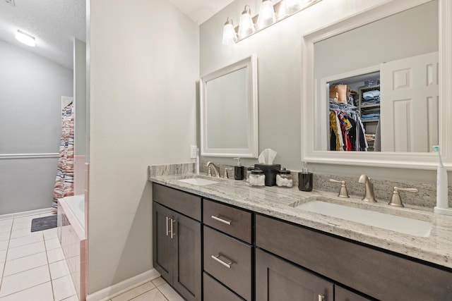 bathroom featuring vanity, a washtub, a textured ceiling, and tile patterned flooring