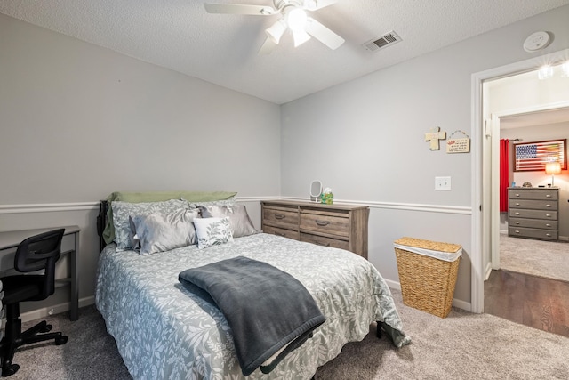 carpeted bedroom with ceiling fan and a textured ceiling