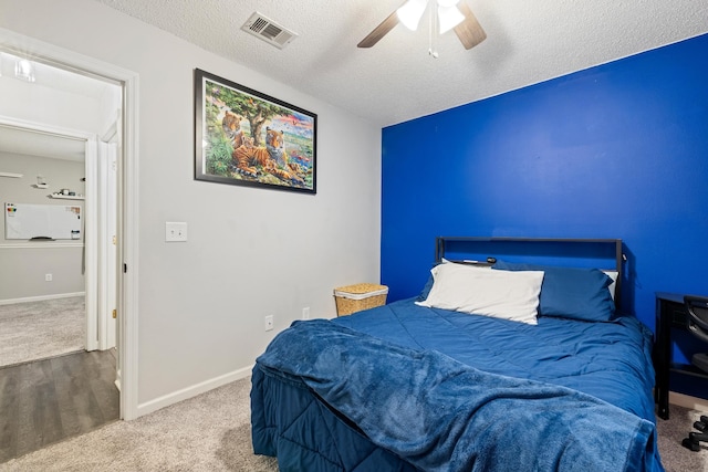 carpeted bedroom with ceiling fan and a textured ceiling