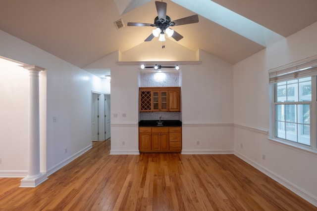 unfurnished living room featuring ornate columns, ceiling fan, sink, light hardwood / wood-style flooring, and vaulted ceiling