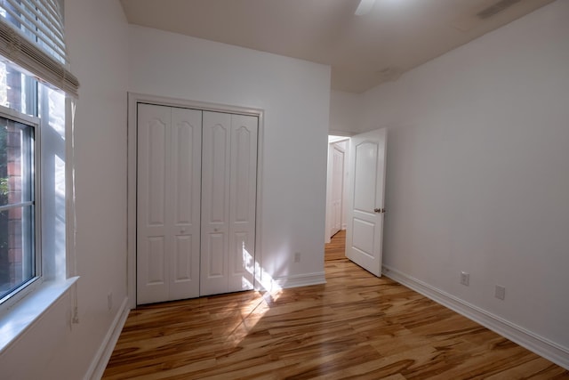 unfurnished bedroom with light wood-type flooring, a closet, and ceiling fan