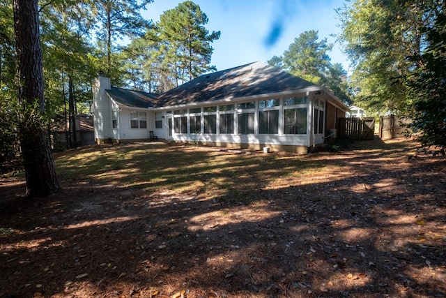 back of house with a sunroom and a lawn