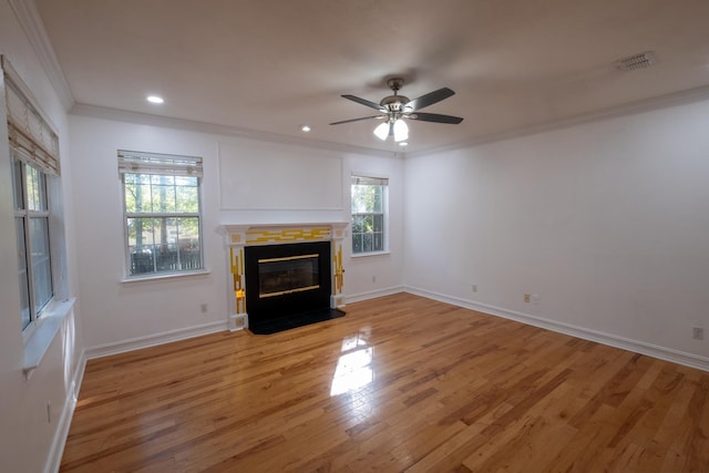 unfurnished living room featuring wood-type flooring, crown molding, and a wealth of natural light