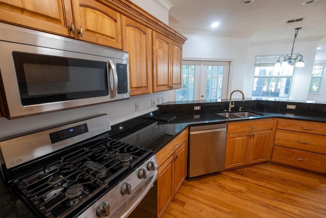 kitchen featuring appliances with stainless steel finishes, light wood-type flooring, crown molding, sink, and a chandelier