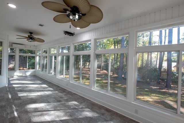 unfurnished sunroom with a wall mounted air conditioner, a wealth of natural light, and ceiling fan