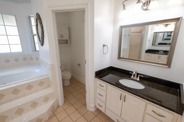 bathroom with tile patterned floors, vanity, a relaxing tiled tub, and toilet