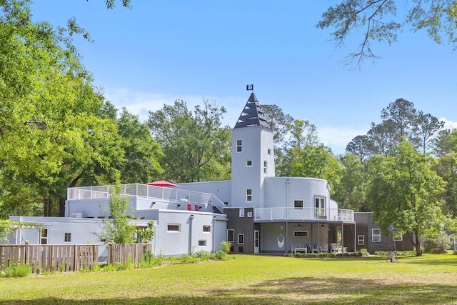 rear view of house featuring a lawn and a balcony