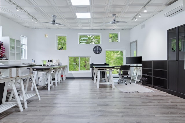 home office with hardwood / wood-style floors, a high ceiling, a wall mounted AC, and ceiling fan