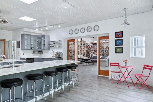 kitchen featuring sink, a breakfast bar, kitchen peninsula, wood-type flooring, and gray cabinets