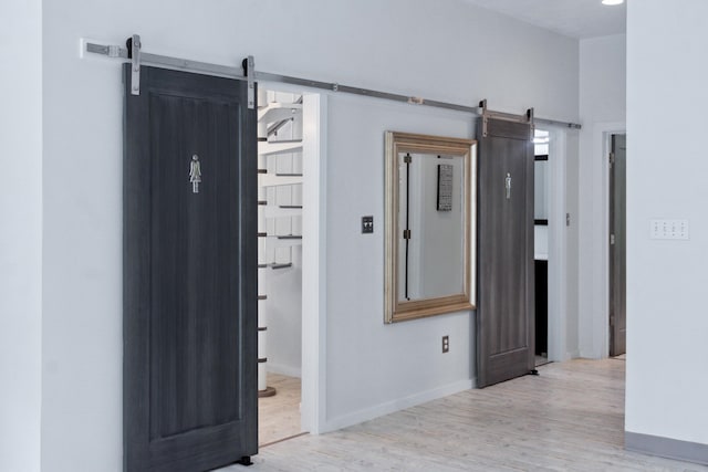 hall with a barn door and light hardwood / wood-style floors