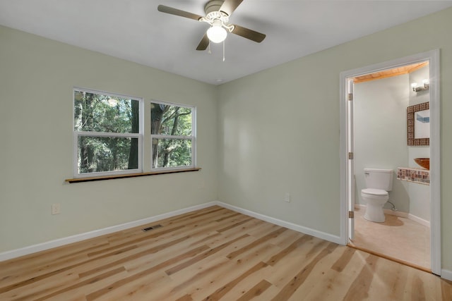 unfurnished bedroom featuring ceiling fan, ensuite bathroom, and light hardwood / wood-style flooring