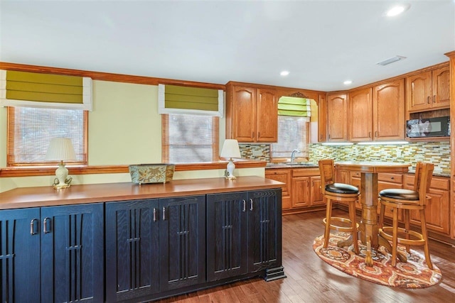 kitchen with ornamental molding, sink, backsplash, and light hardwood / wood-style floors