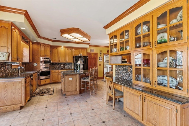 kitchen featuring a breakfast bar, a kitchen island, ornamental molding, black fridge, and decorative backsplash