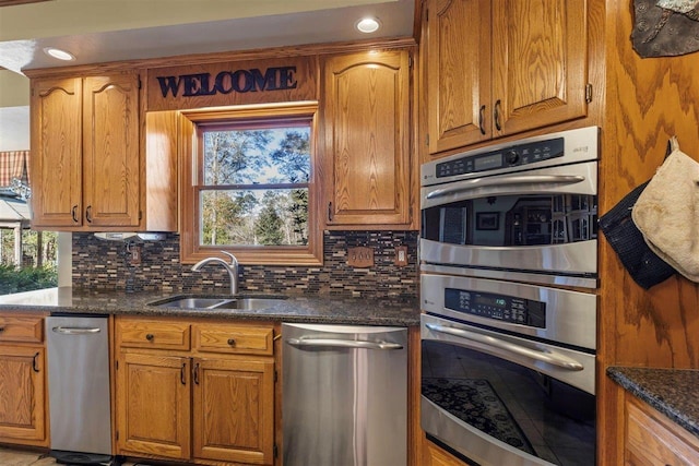 kitchen with a healthy amount of sunlight, stainless steel appliances, sink, and dark stone counters