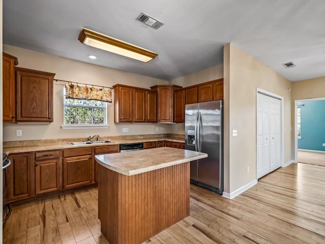 kitchen with sink, light hardwood / wood-style flooring, stainless steel appliances, and a kitchen island