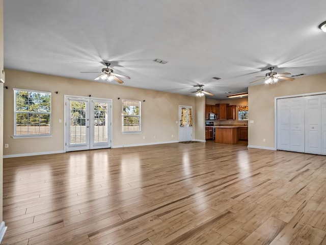 unfurnished living room with light wood-type flooring and french doors