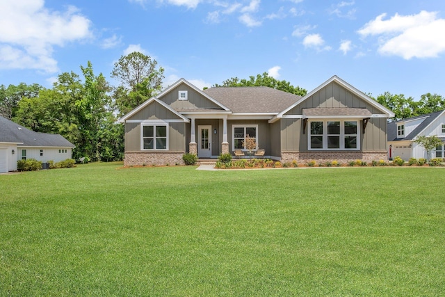 craftsman house with brick siding, a shingled roof, a front lawn, and board and batten siding