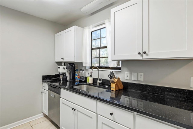 kitchen with dark stone counters, white cabinets, sink, stainless steel dishwasher, and light tile patterned floors