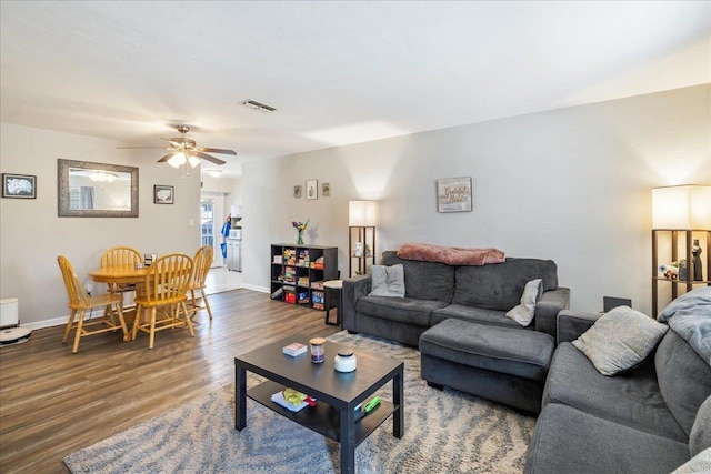 living room with ceiling fan and dark wood-type flooring