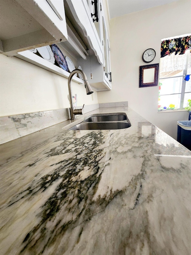 kitchen featuring light stone counters, sink, and white cabinets