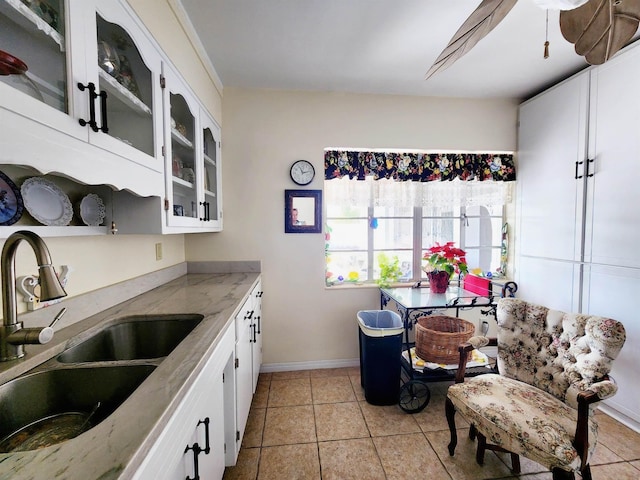 kitchen featuring sink, light tile patterned floors, and white cabinets