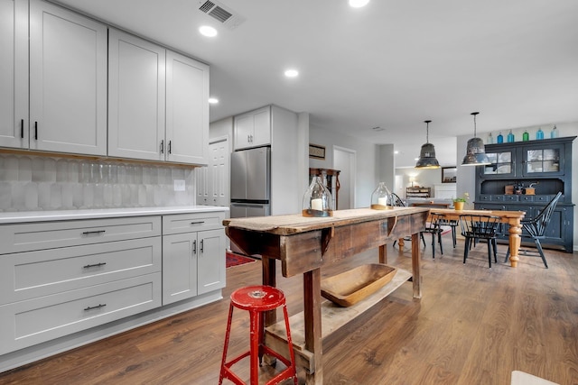 kitchen featuring visible vents, wood finished floors, freestanding refrigerator, decorative light fixtures, and light countertops