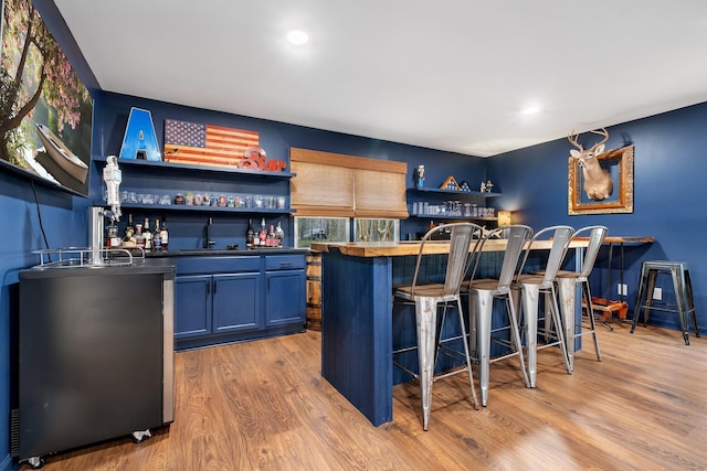 bar featuring a sink, light wood finished floors, and indoor wet bar