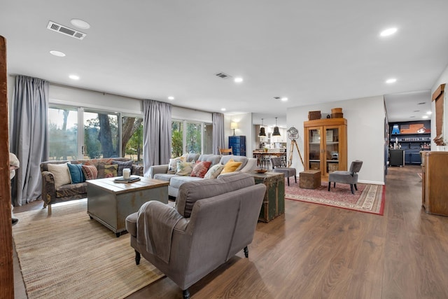 living area featuring a wealth of natural light, visible vents, and wood finished floors