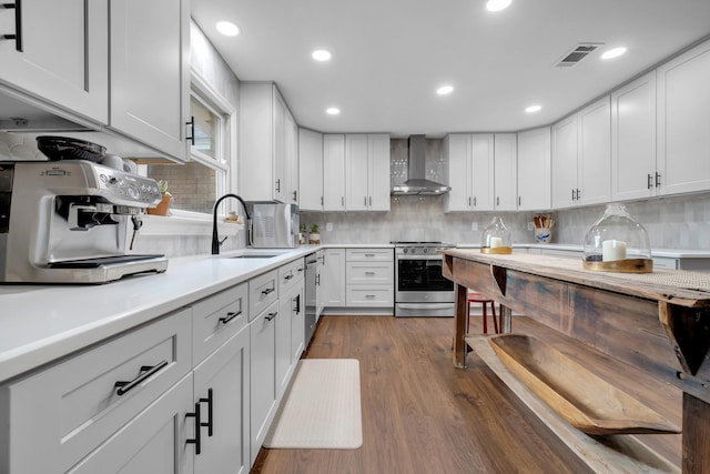 kitchen with white cabinets, wall chimney range hood, and stainless steel appliances