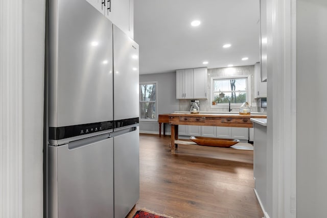 kitchen featuring freestanding refrigerator, a healthy amount of sunlight, white cabinetry, and wood finished floors