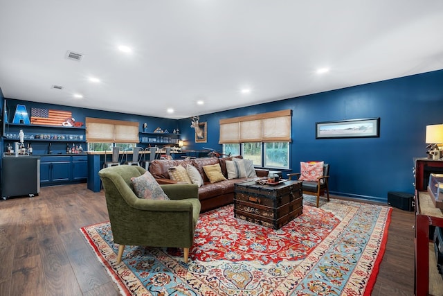 living area with recessed lighting, bar area, visible vents, and wood finished floors