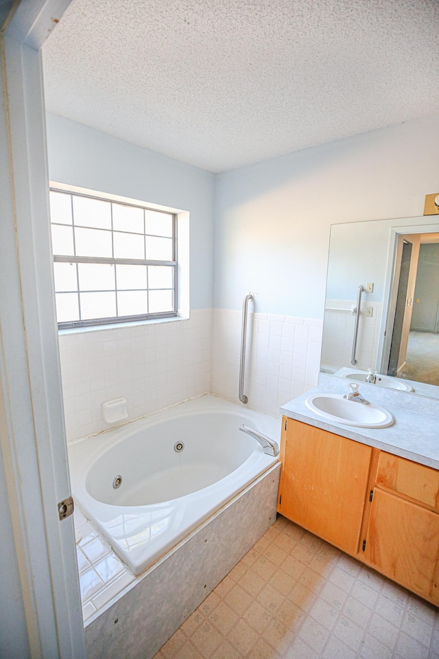 bathroom featuring vanity, a textured ceiling, and tiled bath