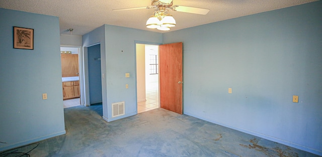 carpeted spare room with a textured ceiling and ceiling fan