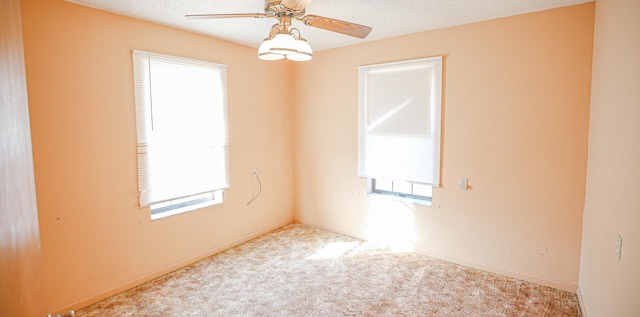 carpeted empty room featuring a textured ceiling, ceiling fan, and plenty of natural light