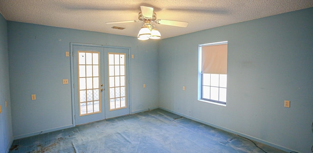 carpeted spare room featuring ceiling fan, french doors, and a textured ceiling