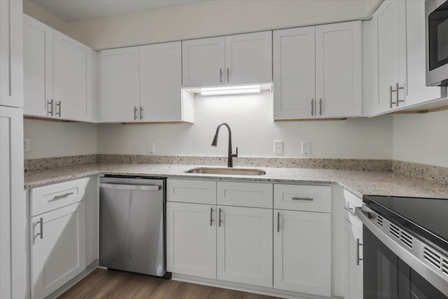 5400 Debbie Dr, Tallahassee, FL 32310 - kitchen featuring stainless steel appliances, a sink, white cabinets, wood finished floors, and light stone countertops