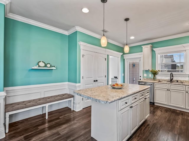 kitchen with a kitchen island, a sink, light countertops, stainless steel dishwasher, and decorative light fixtures