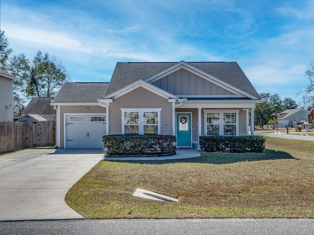 view of front of property featuring driveway, an attached garage, fence, a front lawn, and board and batten siding