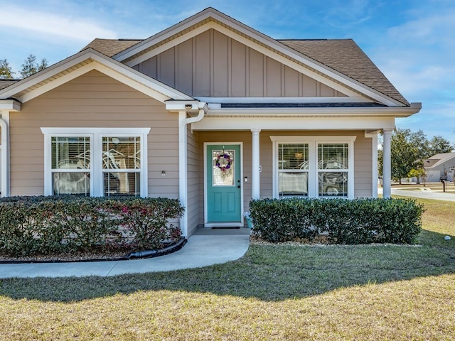 view of front of property with a shingled roof, board and batten siding, and a front yard