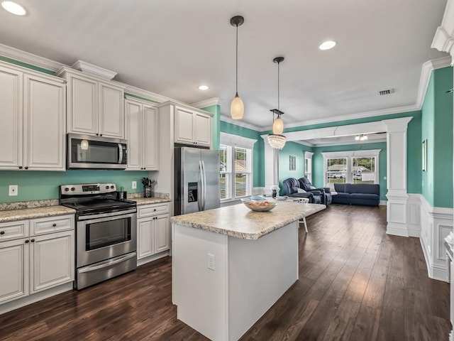 kitchen with appliances with stainless steel finishes, open floor plan, light countertops, and ornate columns